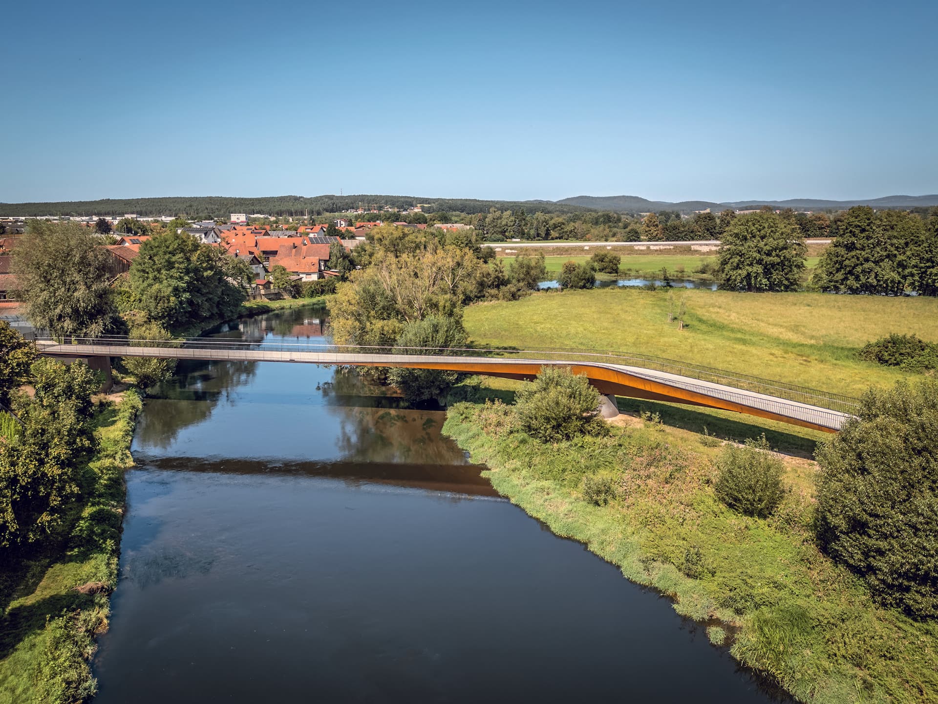 Was am Boden verschmilzt, wird aus der Luft sichtbar: die Brücke als feine Linie im Gefüge aus Natur, Stadt und Wasserlauf. (© FOTOGRAFIEIMRAUM)